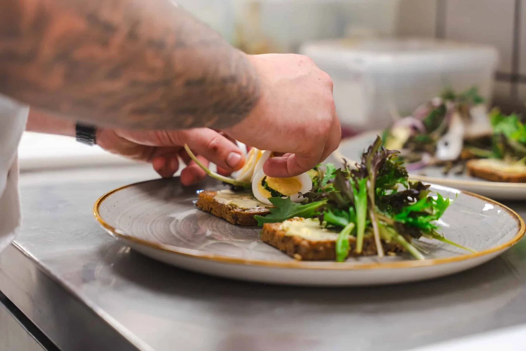 Representative hotel space: A plated meal is being garnished with greens on a kitchen counter.