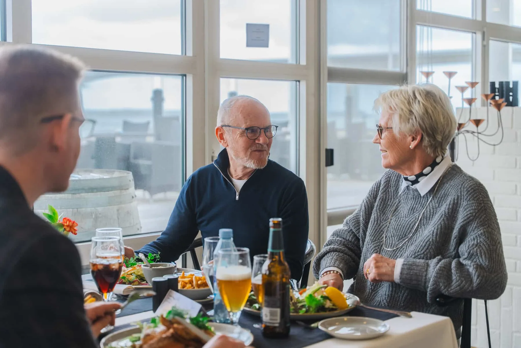 Representative hotel space: People share a meal at a table beside large windows.