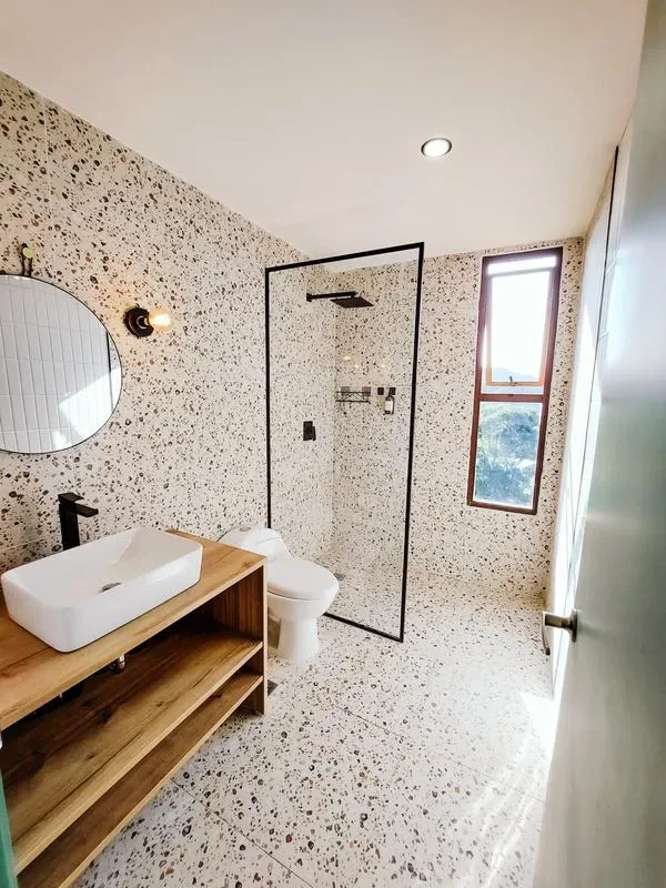 A bright bathroom with a sink, toilet, and glass shower.
