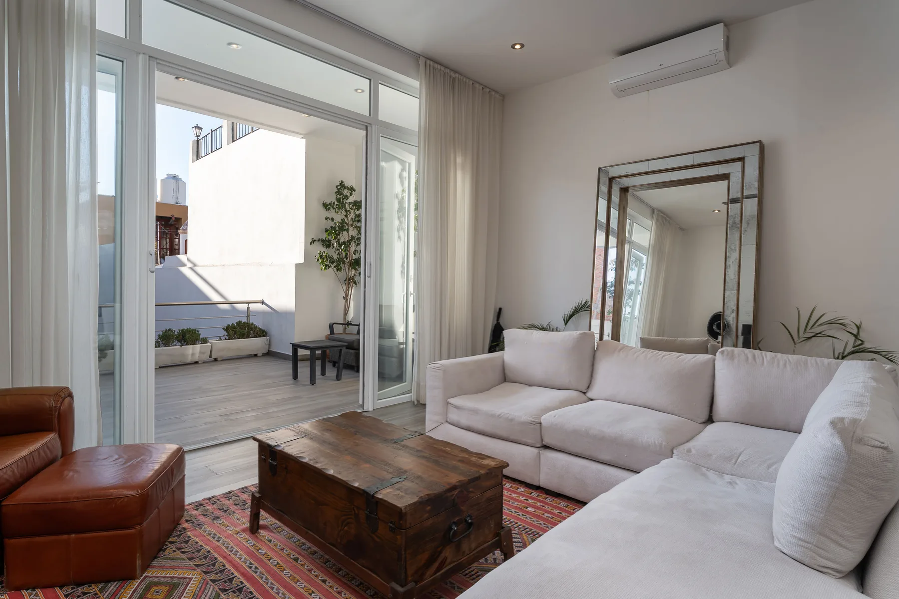 A bright living room with seating, a wooden coffee table, and sliding glass doors to a patio.