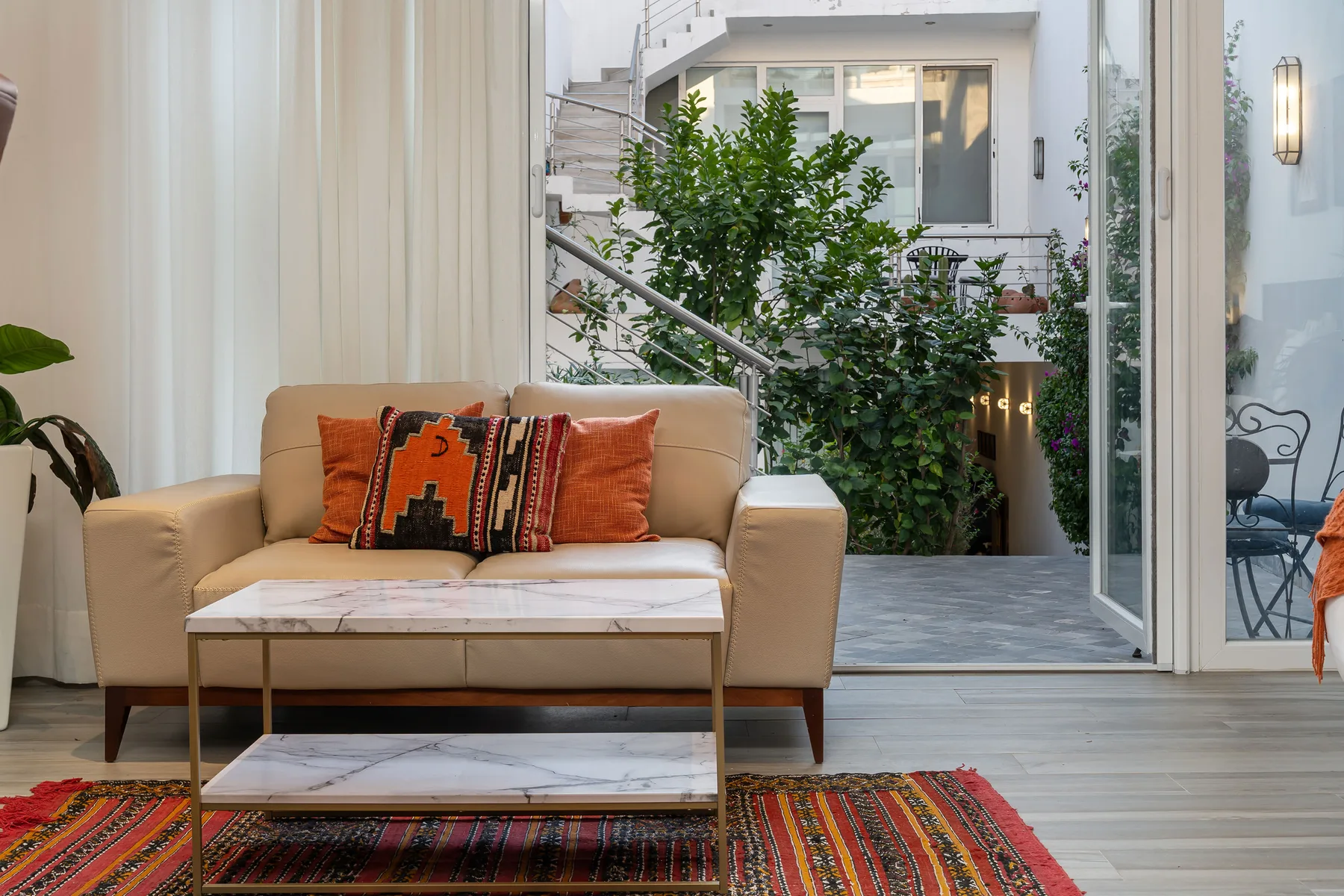A bright sitting area opens onto a courtyard, with a sofa and coffee table.