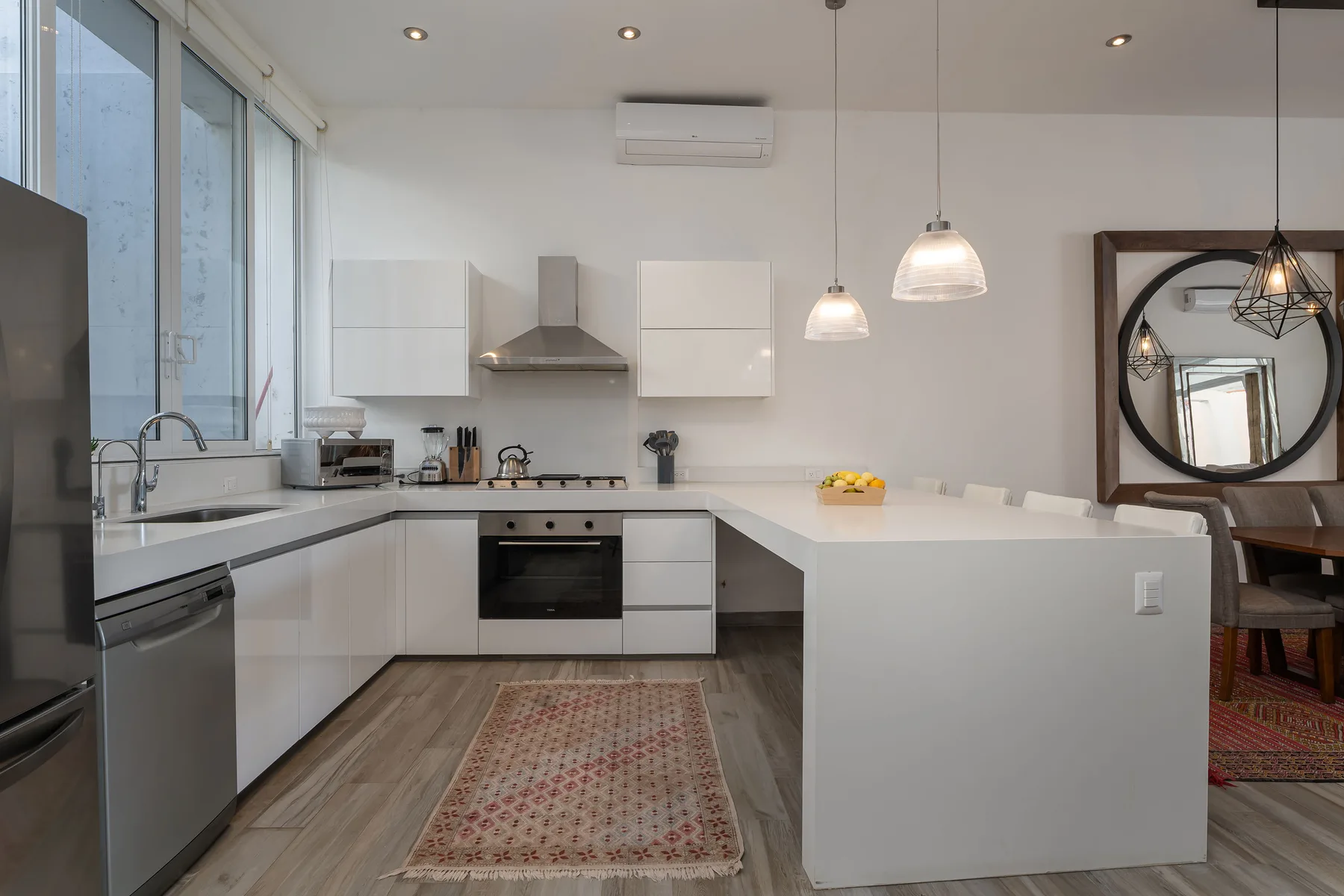 A bright modern kitchen with white cabinets, a cooking area, and a large island.