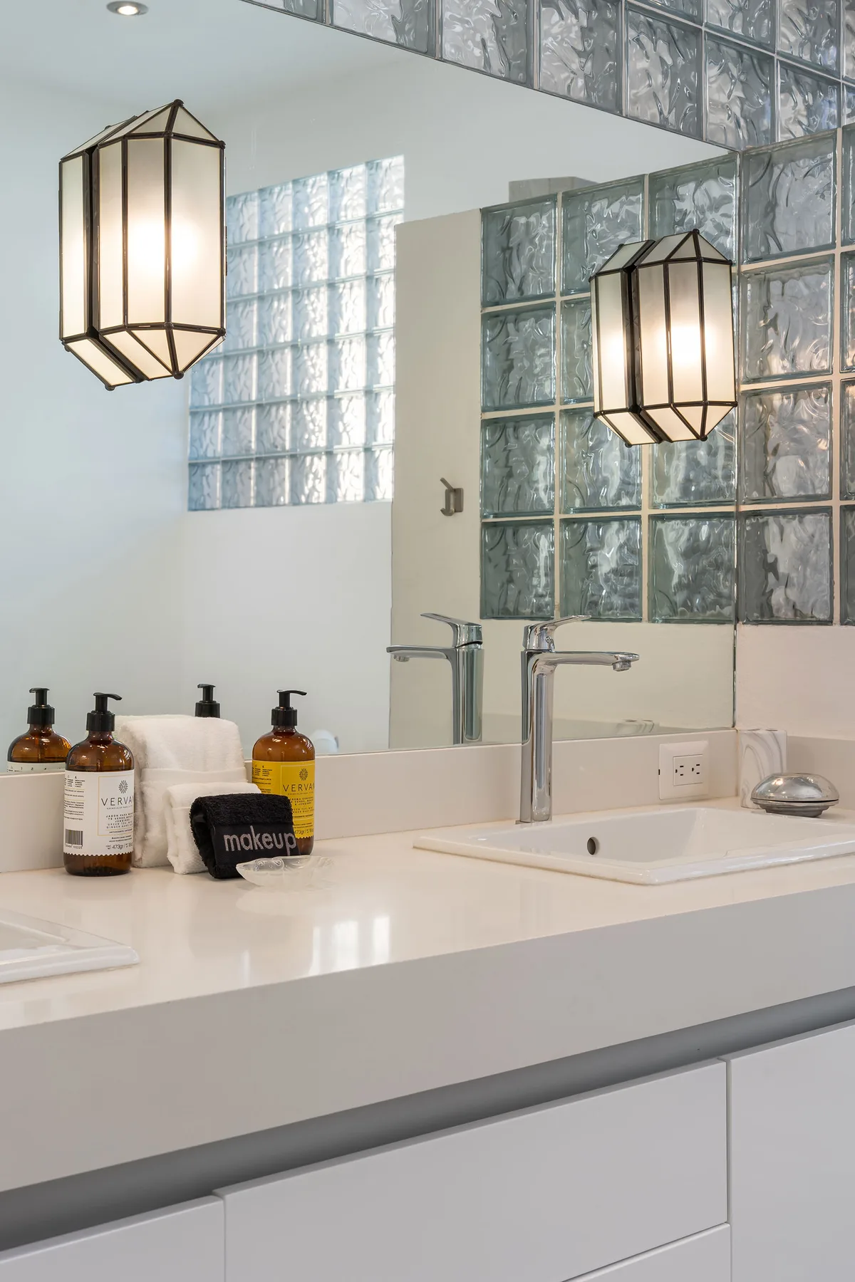 A bright bathroom vanity with a wide sink and glass block windows.
