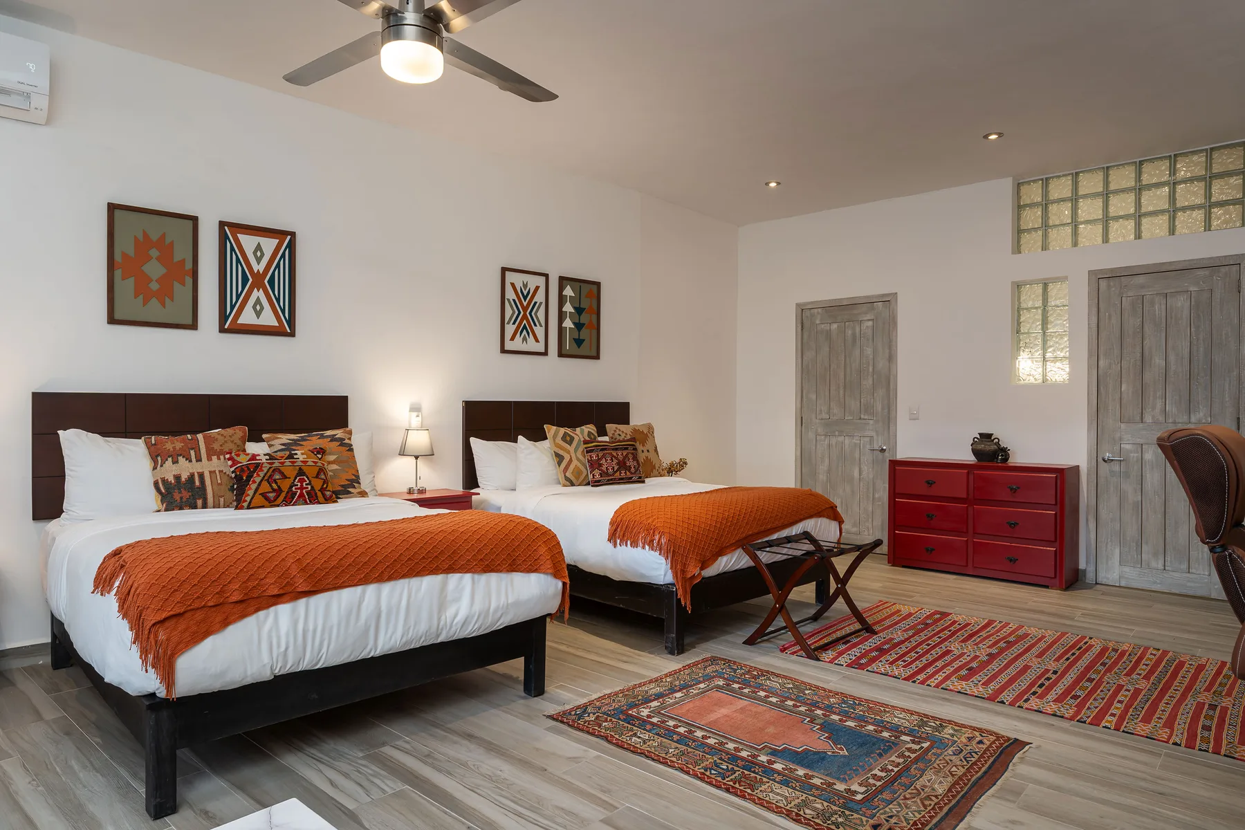 A bedroom with two beds, colorful patterned bedding, and rugs on the floor.