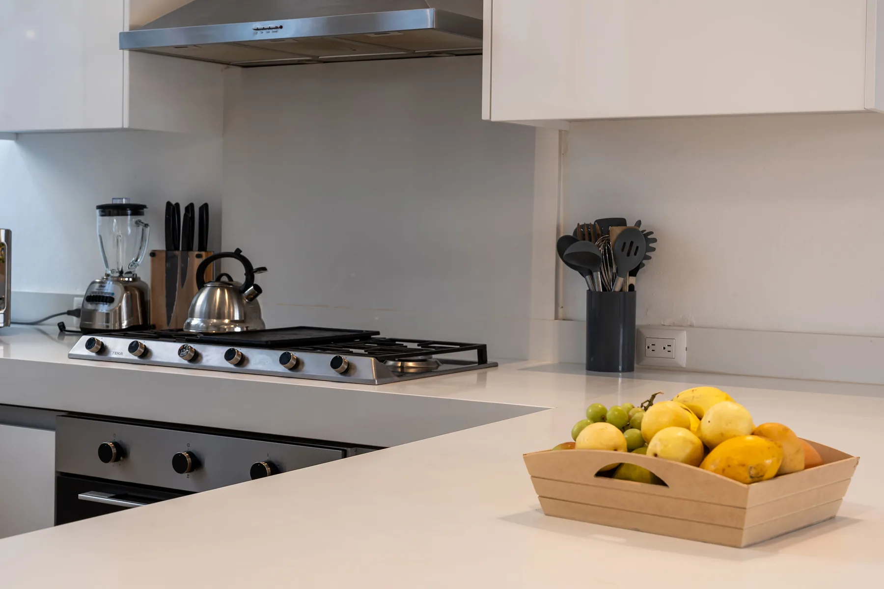 A bright kitchen with a gas cooktop and a bowl of fruit on the counter.