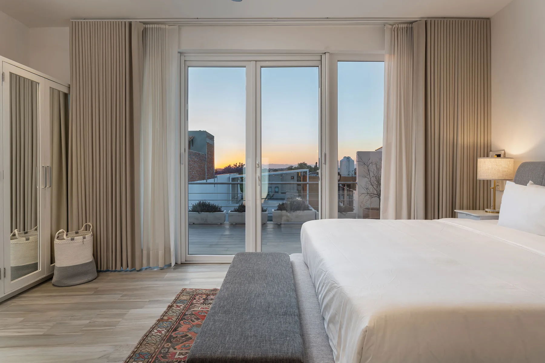 A bedroom with a large bed, mirrored wardrobe, and glass doors opening onto a balcony.