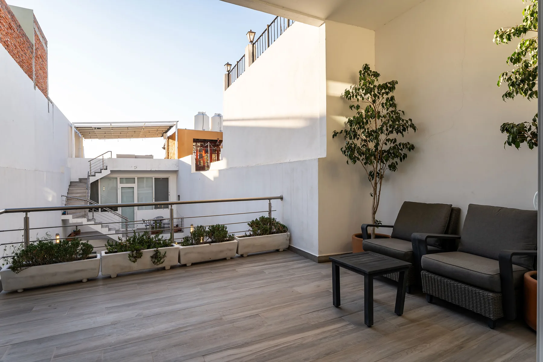 An outdoor patio with seating, planters, and potted trees.