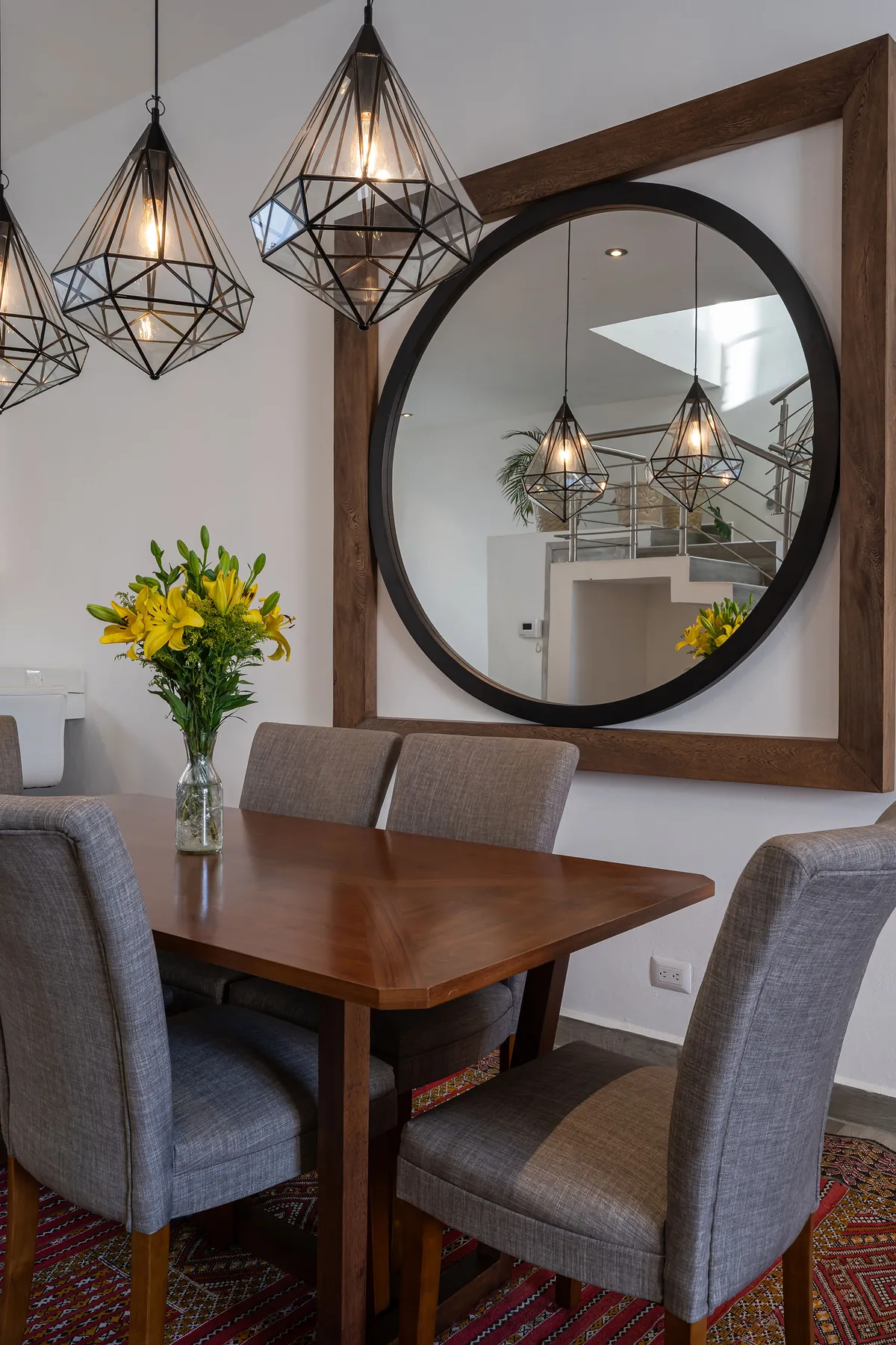 A dining area with a wooden table, upholstered seating, and pendant lights.