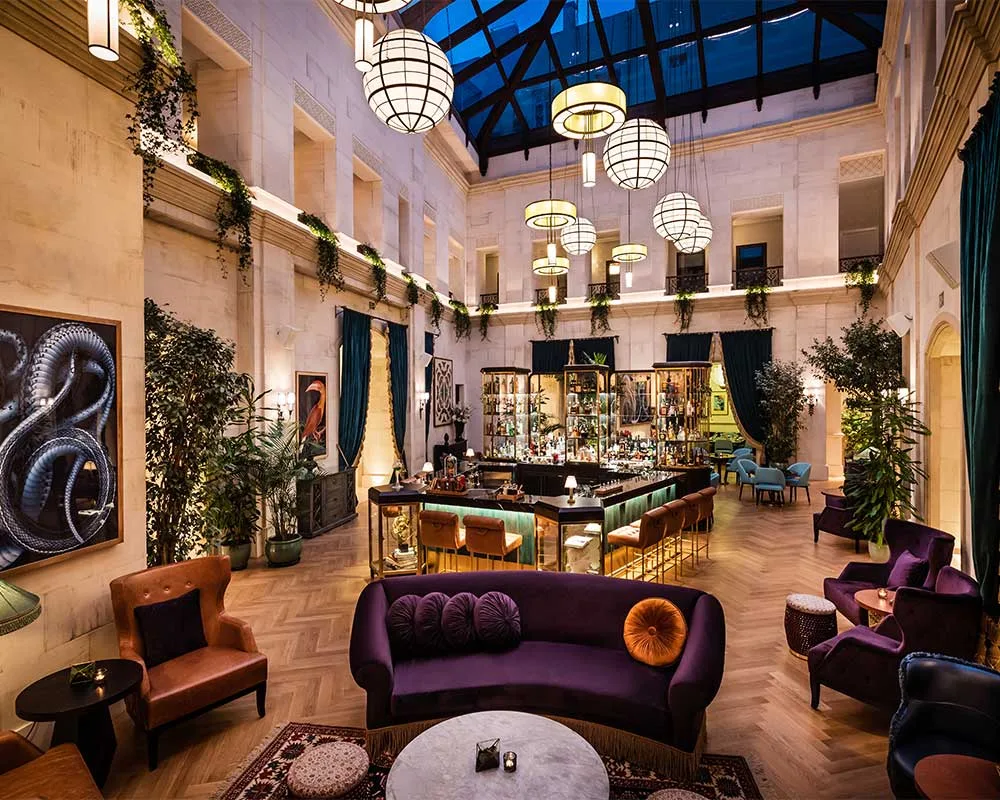 Espacio representativo del hotel: Un salón de hotel con una barra central, asientos y un techo acristalado.