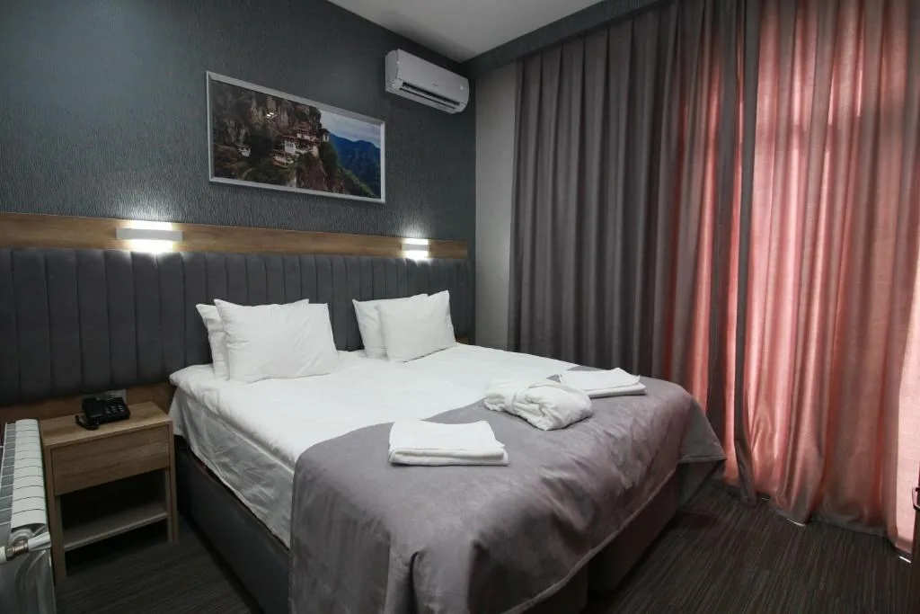 Espacio representativo del hotel: Dormitorio con una cama, una mesita de noche y cortinas largas.