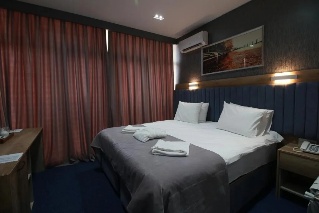 Espacio representativo del hotel: Dormitorio con cama doble vestida con ropa de cama blanca y gris.