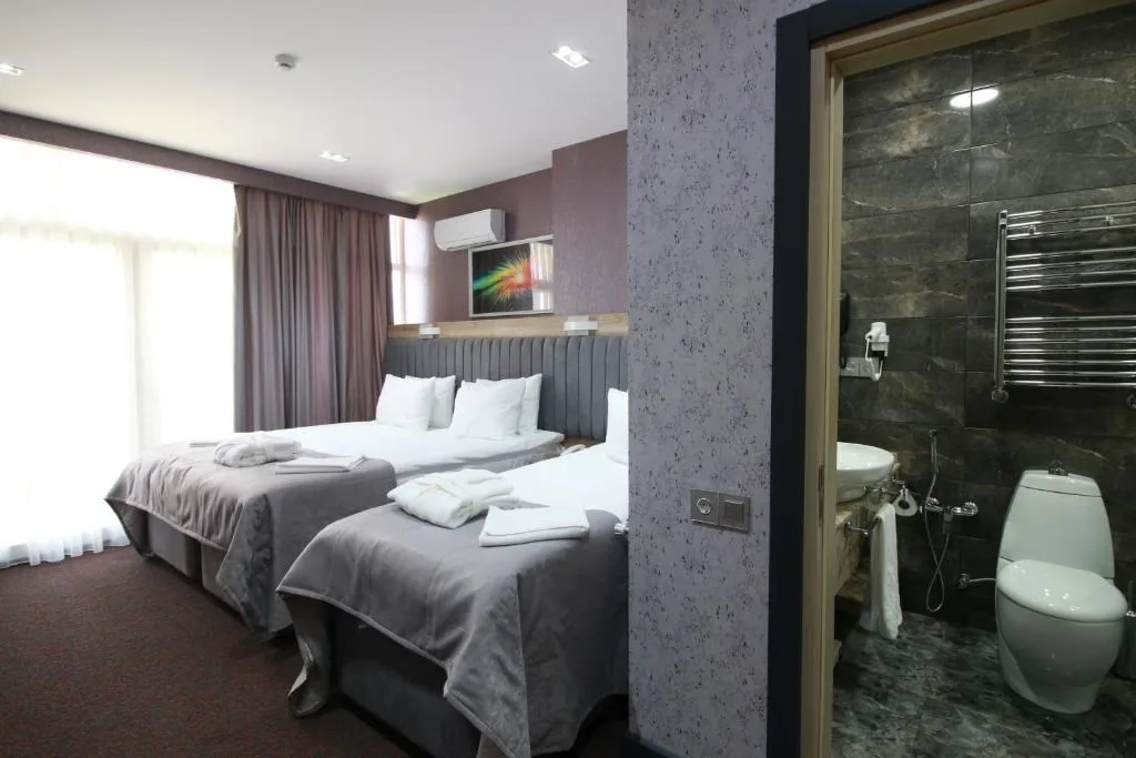 Espacio representativo del hotel: Un dormitorio de hotel con dos camas junto a un baño abierto.