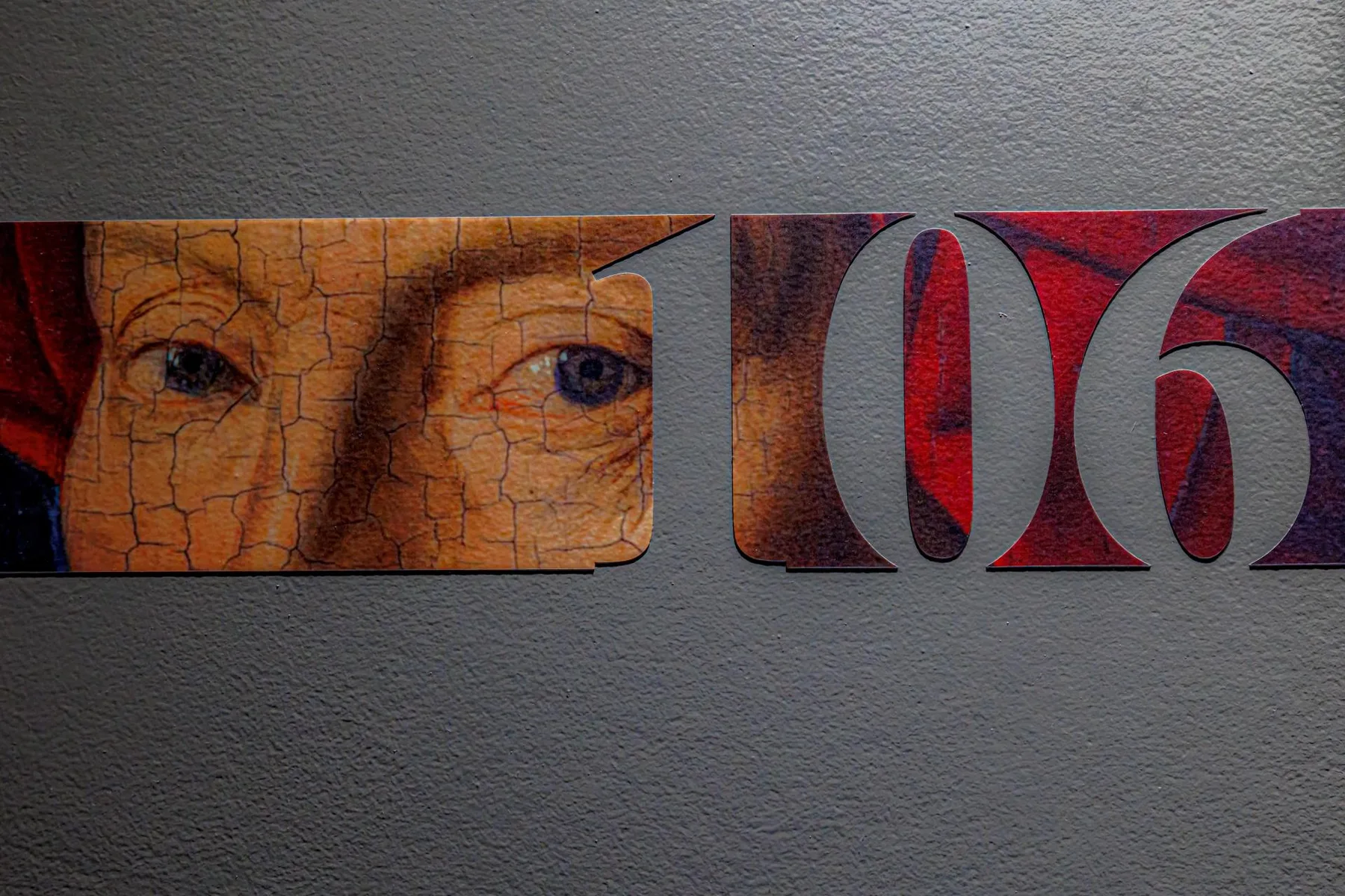 Espacio representativo del hotel: Un primer plano de un mural en la pared con un rostro pintado junto a letras grandes y estilizadas.