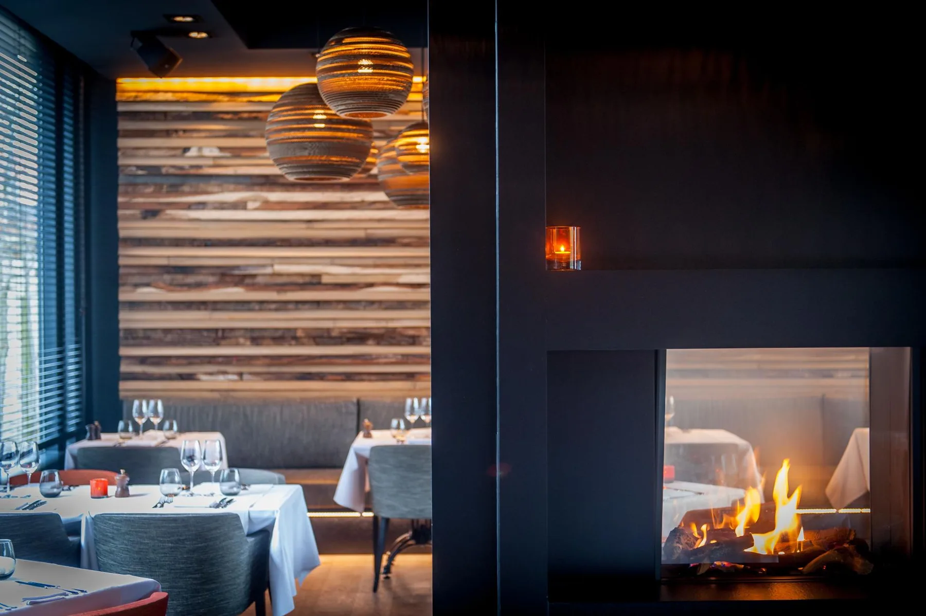 Espacio representativo del hotel: Comedor de restaurante con mesas preparadas junto a una chimenea encendida.