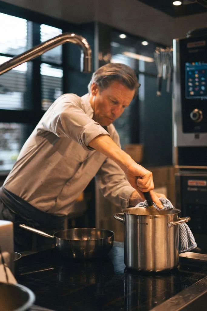 Espacio representativo del hotel: Un hombre cocina en una estufa dentro de una cocina.