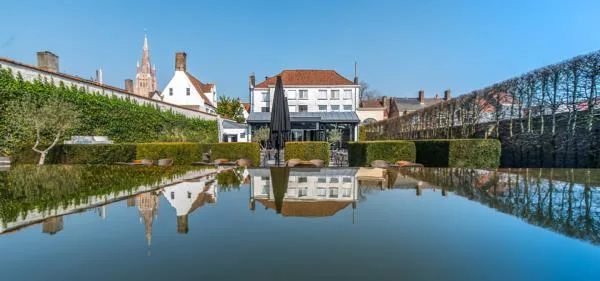 Espacio representativo del hotel: Un edificio moderno y jardines paisajísticos se reflejan en un estanque tranquilo.