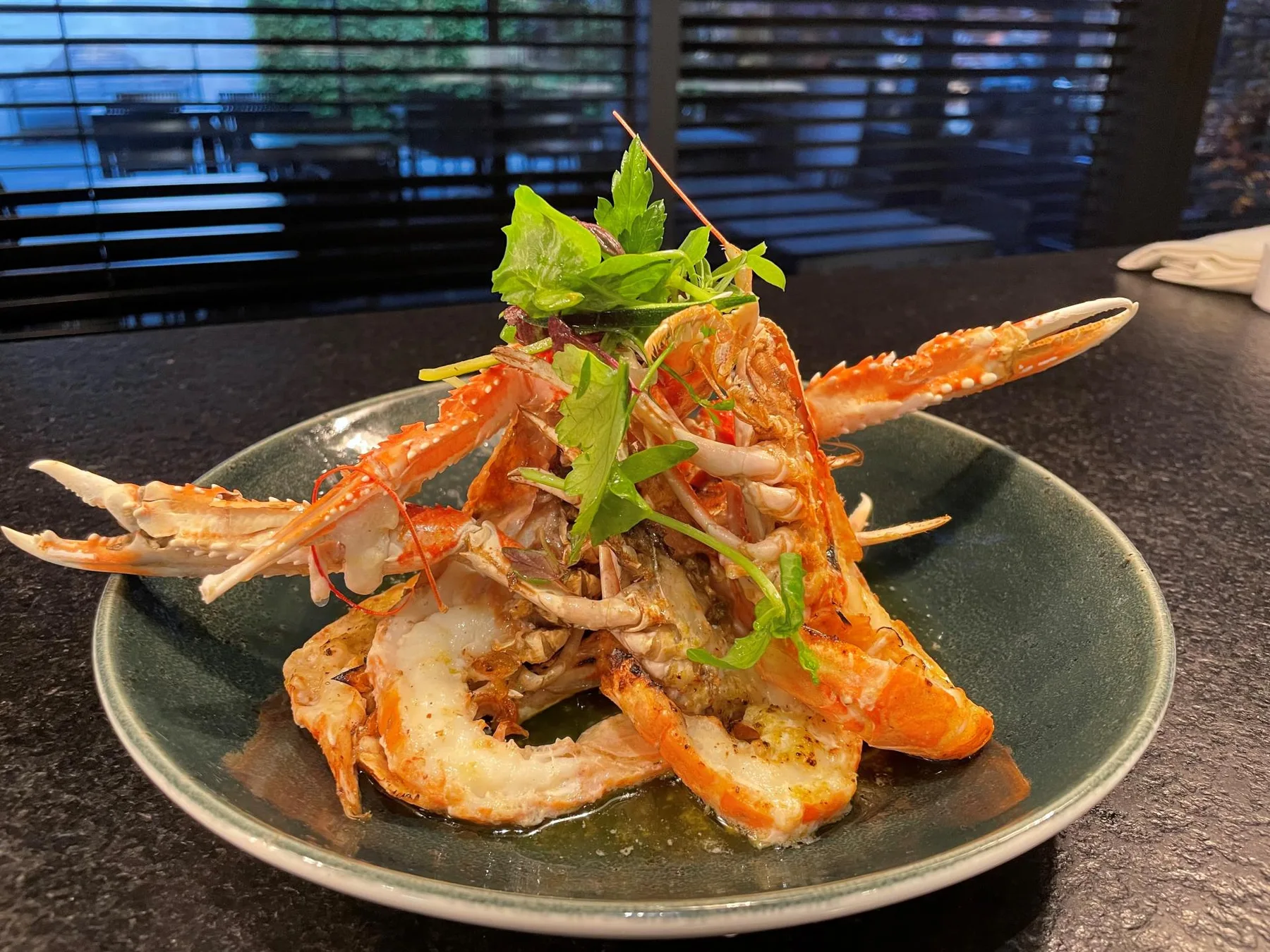 Espacio representativo del hotel: Un plato de mariscos adornado con hojas verdes está sobre una encimera oscura.