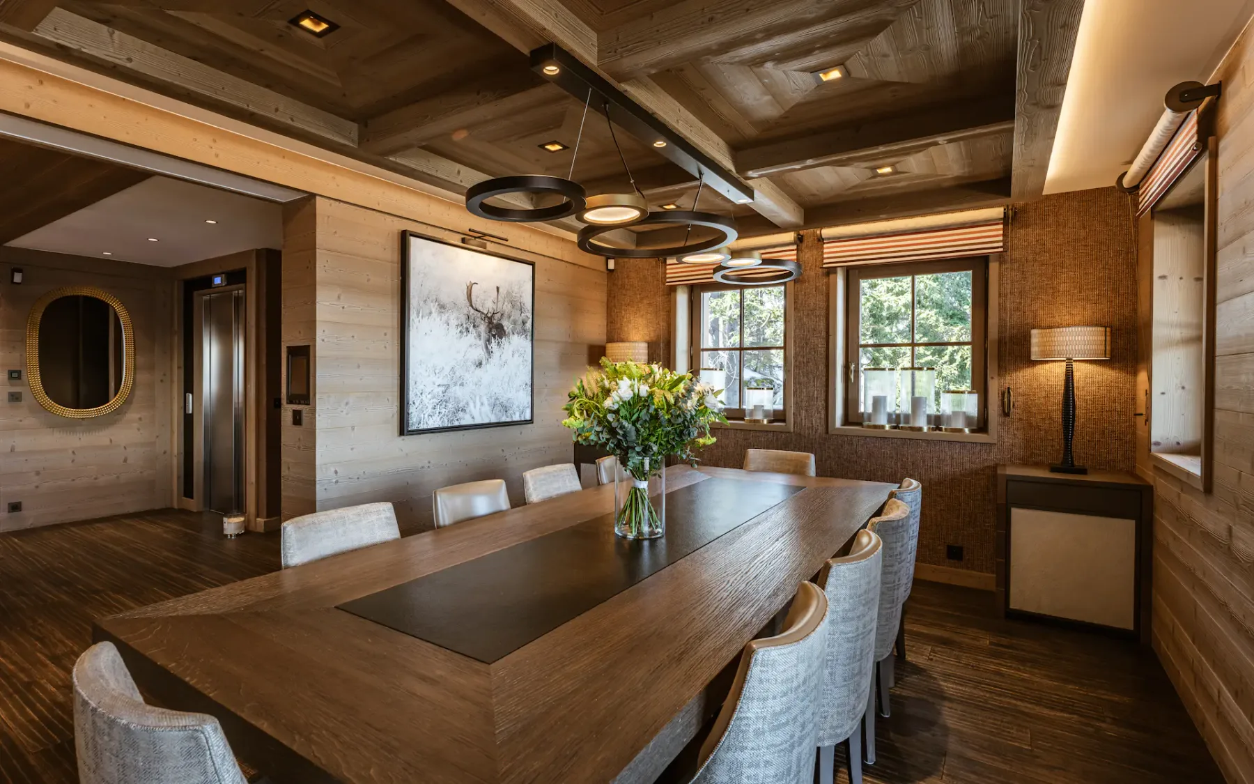 Un comedor con una larga mesa de madera y sillas bajo luces colgantes.