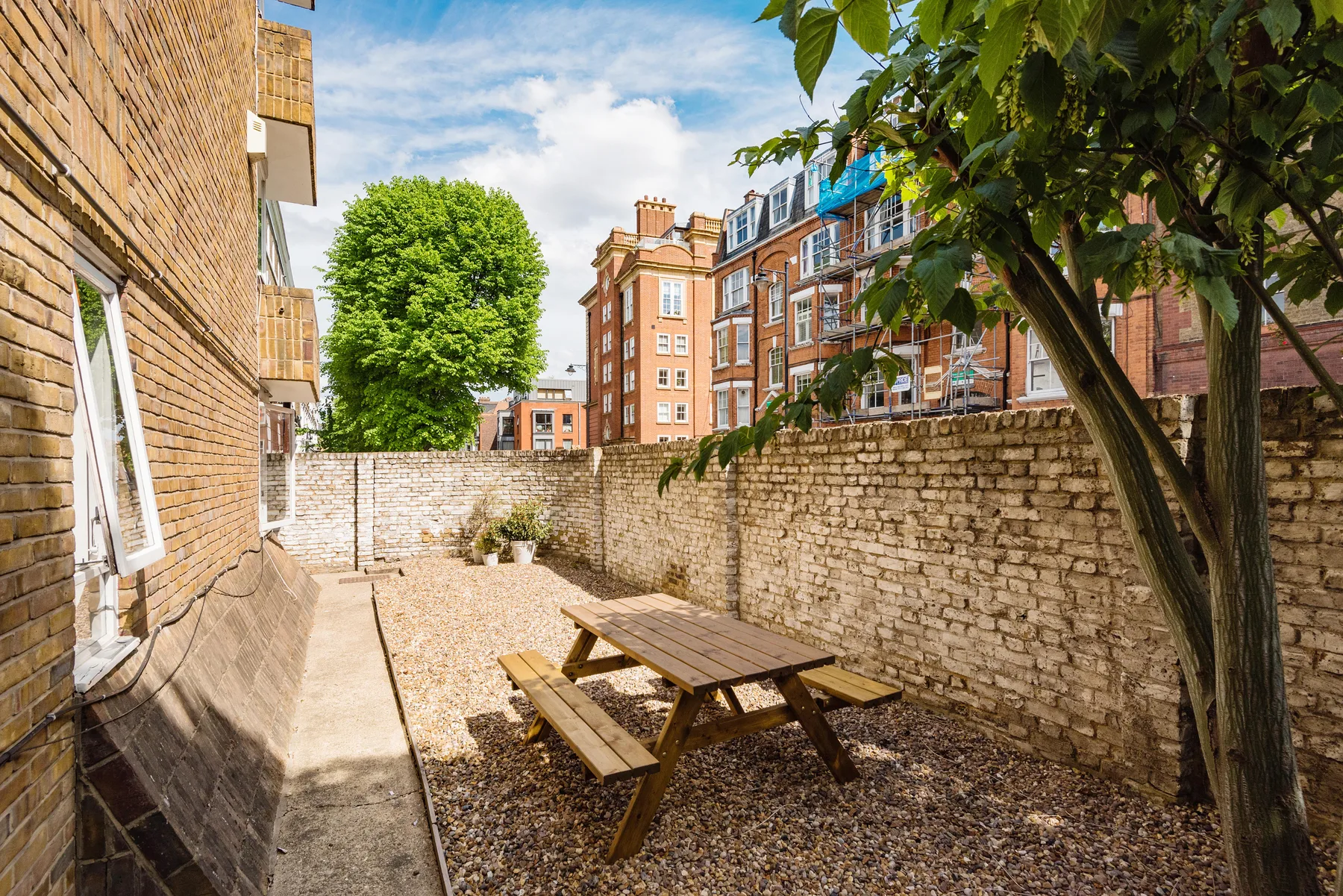 Zona común: Un patio pavimentado con una mesa de picnic de madera y muros de ladrillo.