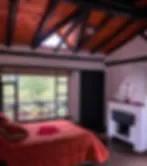 Espacio representativo del hotel: Un dormitorio con una colcha roja, una ventana y una chimenea.