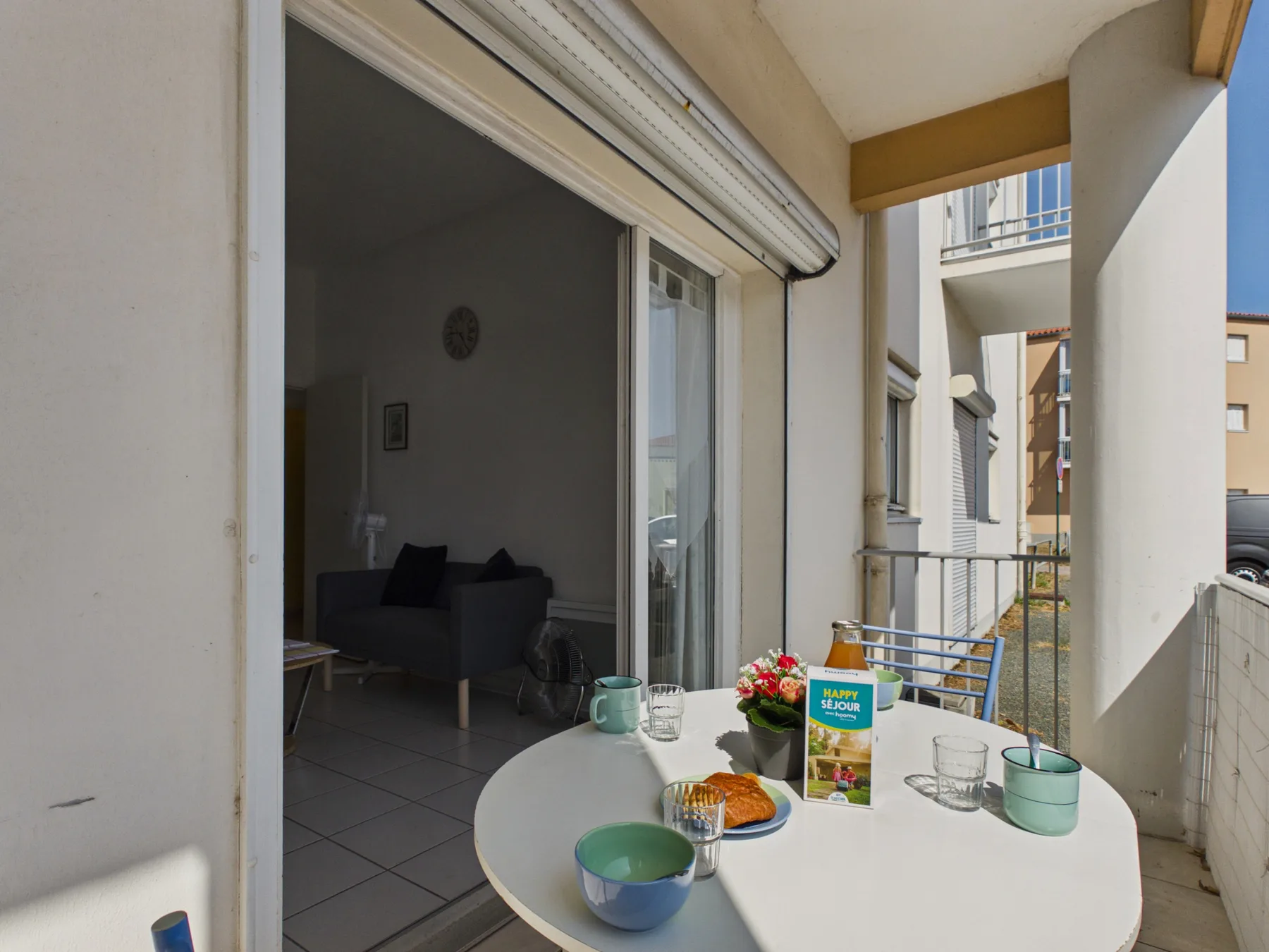 A balcony dining area with a round table set with breakfast items.