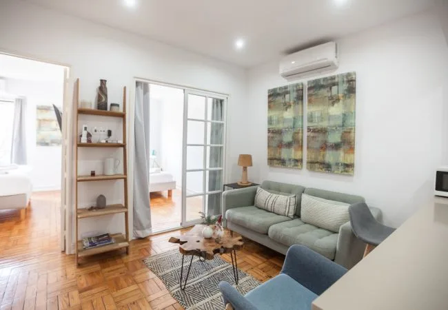 A bright living room with seating, a coffee table, and abstract wall art.