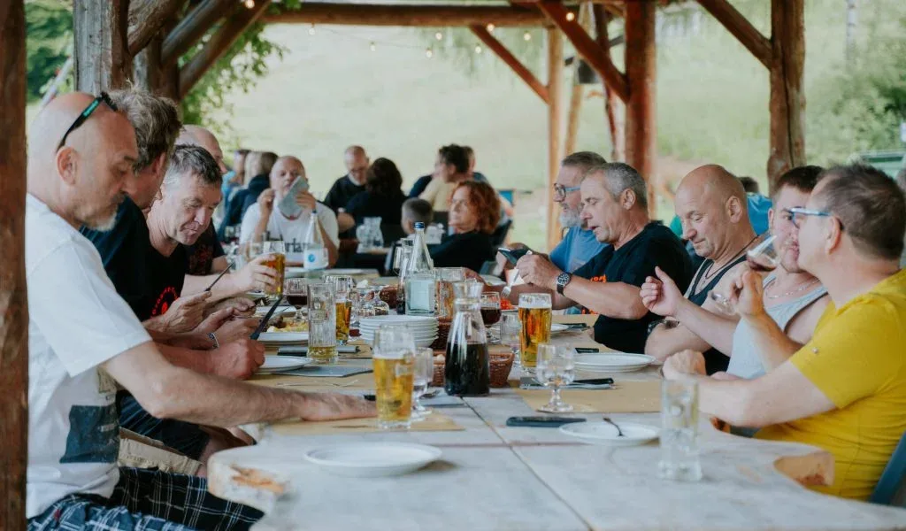 Representative hotel space: People gather around a long table for a meal in a covered outdoor dining area.