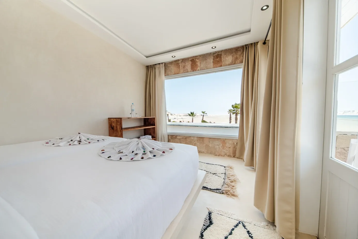 Representative hotel space: A bright bedroom with a large bed and a window overlooking the water.