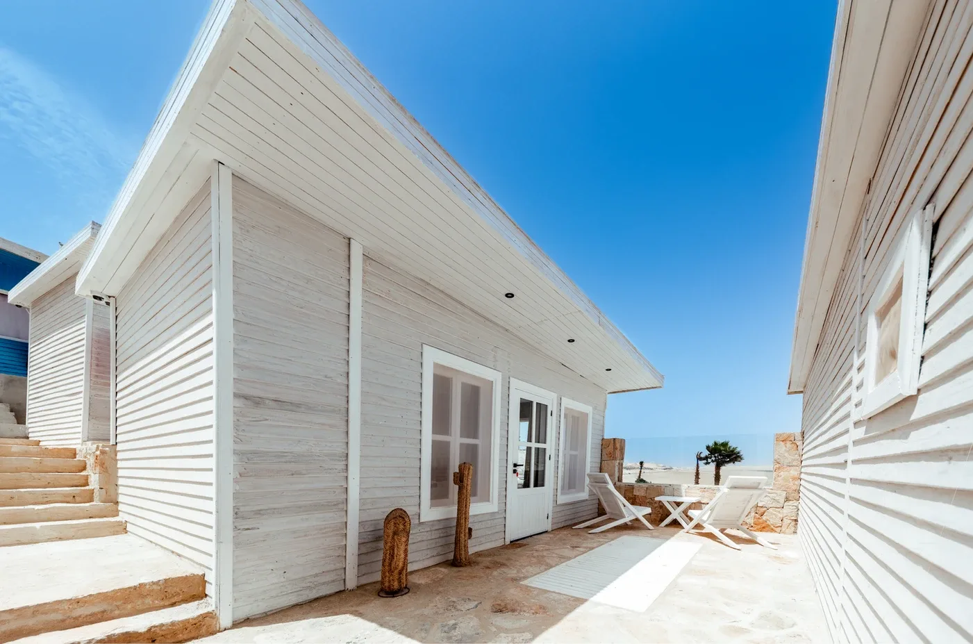 Representative hotel space: A bright outdoor patio between white buildings, with a small table and chairs.