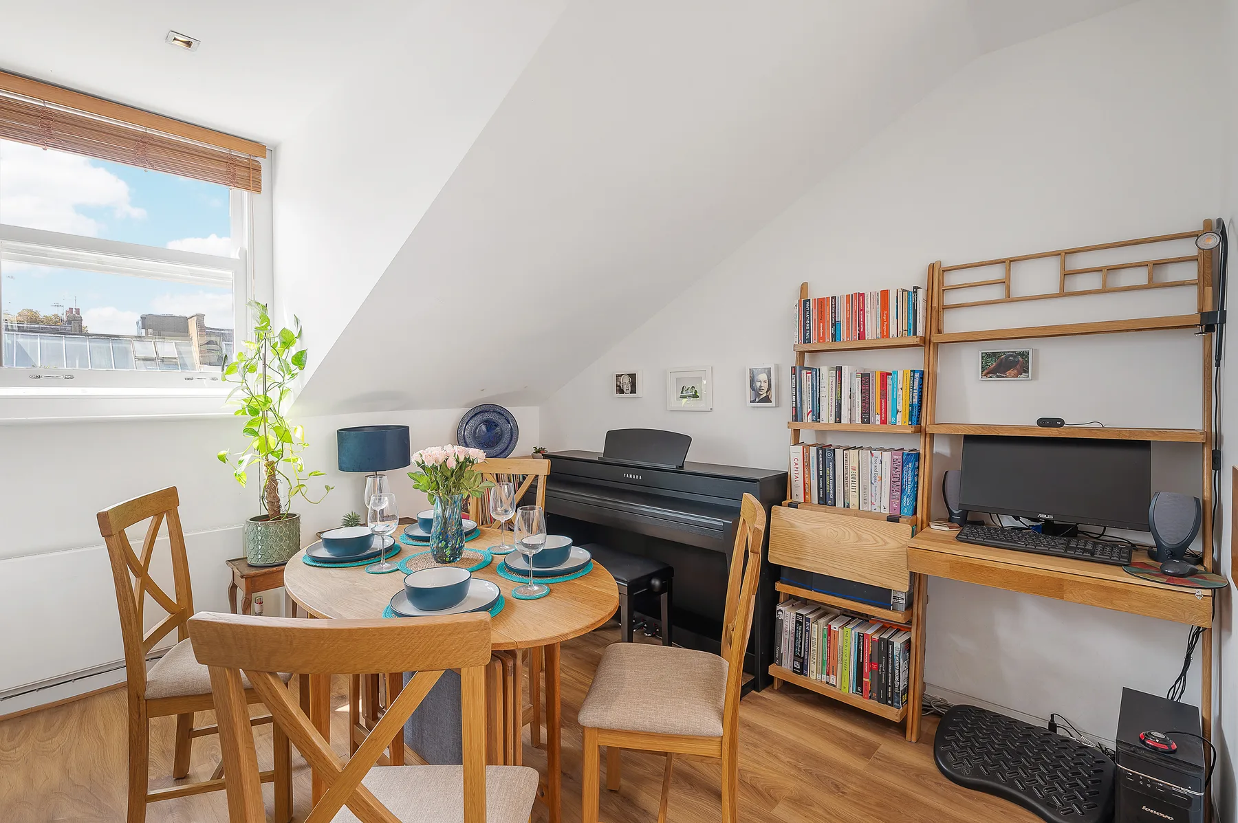 A bright room with a dining table, keyboard, and bookshelves.