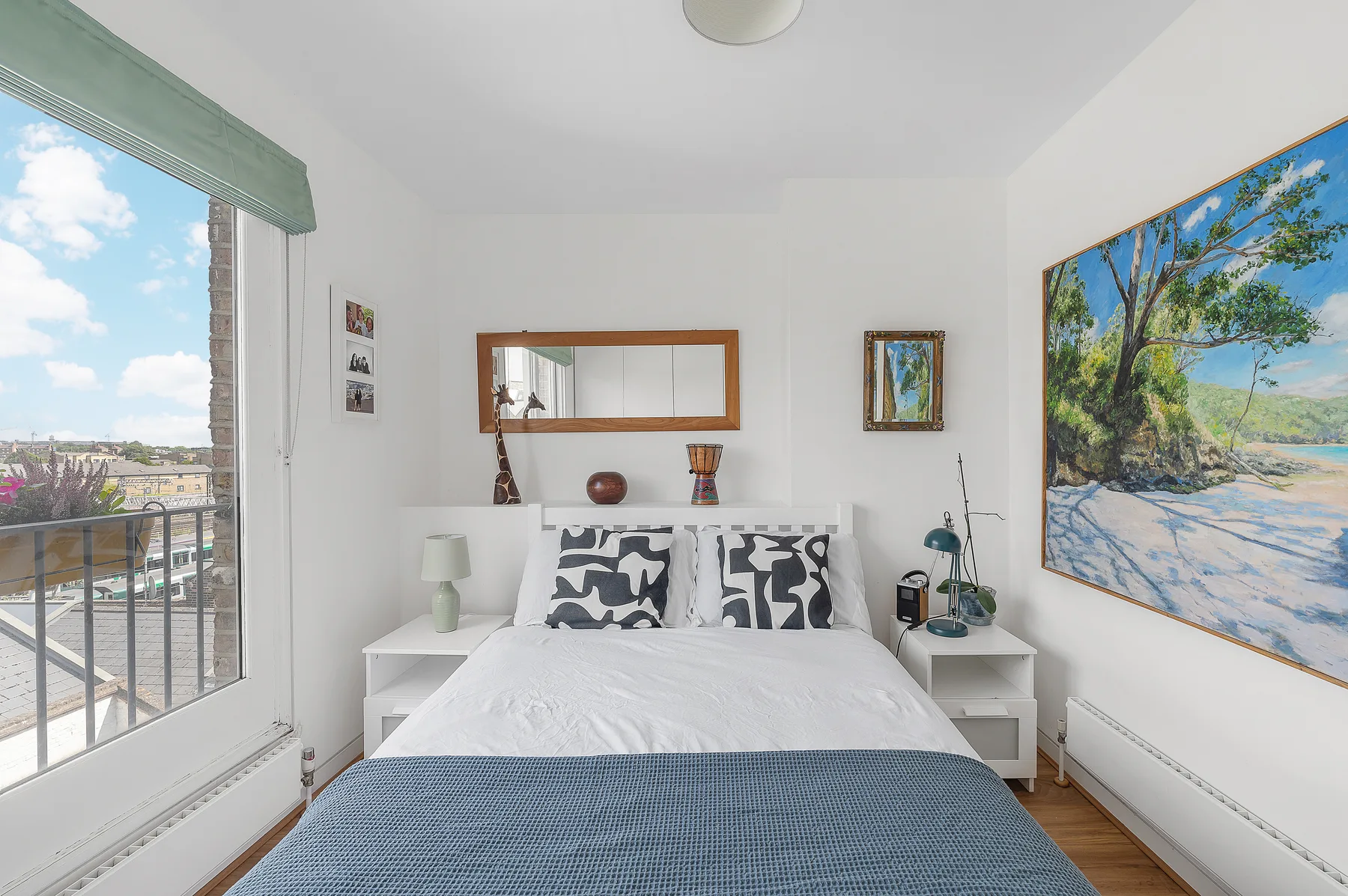 A bright bedroom with a neatly made bed and a large window.