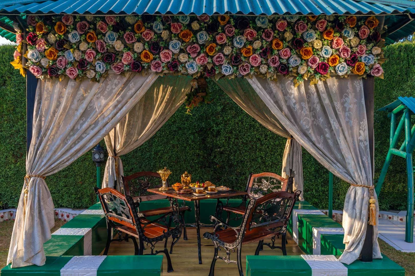 A curtained outdoor dining area has a table surrounded by seating.