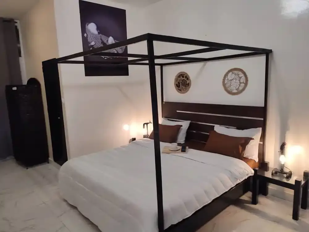 Representative hotel space: A bedroom with a bed beneath a black canopy frame and wall art.