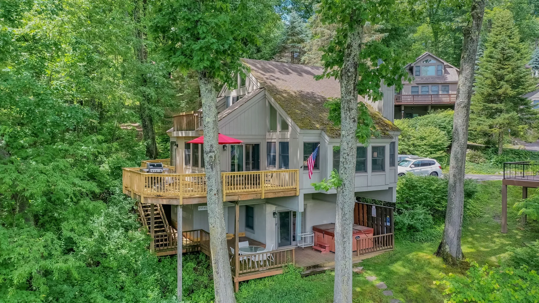 A wooded residential scene with a gray house and raised wooden decks.