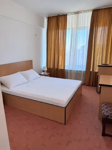 Espacio representativo del hotel: Un dormitorio con una cama y una ventana con cortinas.