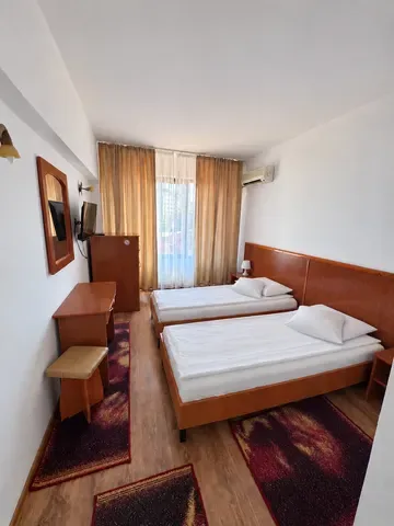 Espacio representativo del hotel: Un dormitorio de hotel con dos camas y una ventana con cortinas.