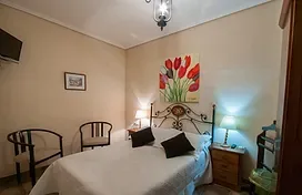 Representative hotel space: A bedroom with a bed, two chairs, and floral wall art.