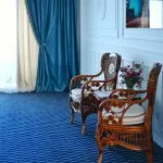 Espacio representativo del hotel: Una zona de estar con sillas de madera junto a una ventana con cortinas.