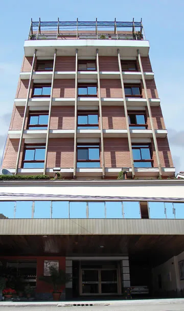 Espacio representativo del hotel: Edificio de ladrillo de varias plantas, con filas de ventanas y una entrada acristalada.