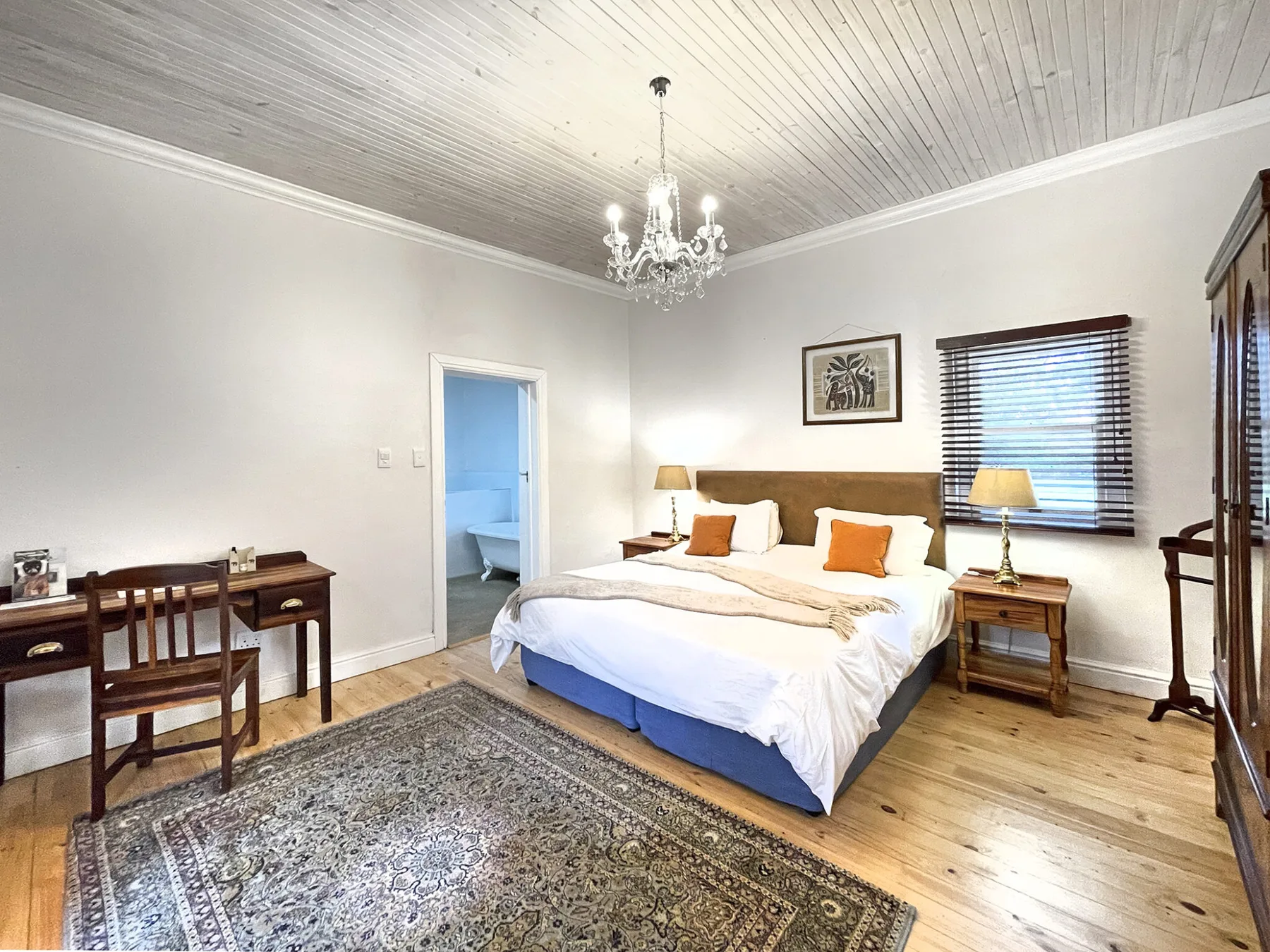 Representative hotel space: A bedroom with a large bed, a writing desk, and a patterned rug.
