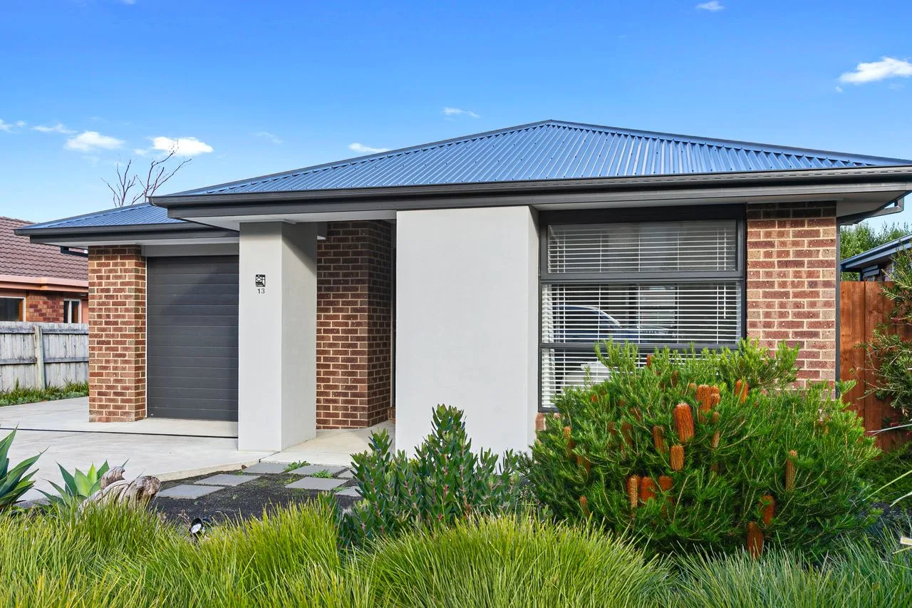 A single-story brick-and-render house with a dark metal roof and front garden.