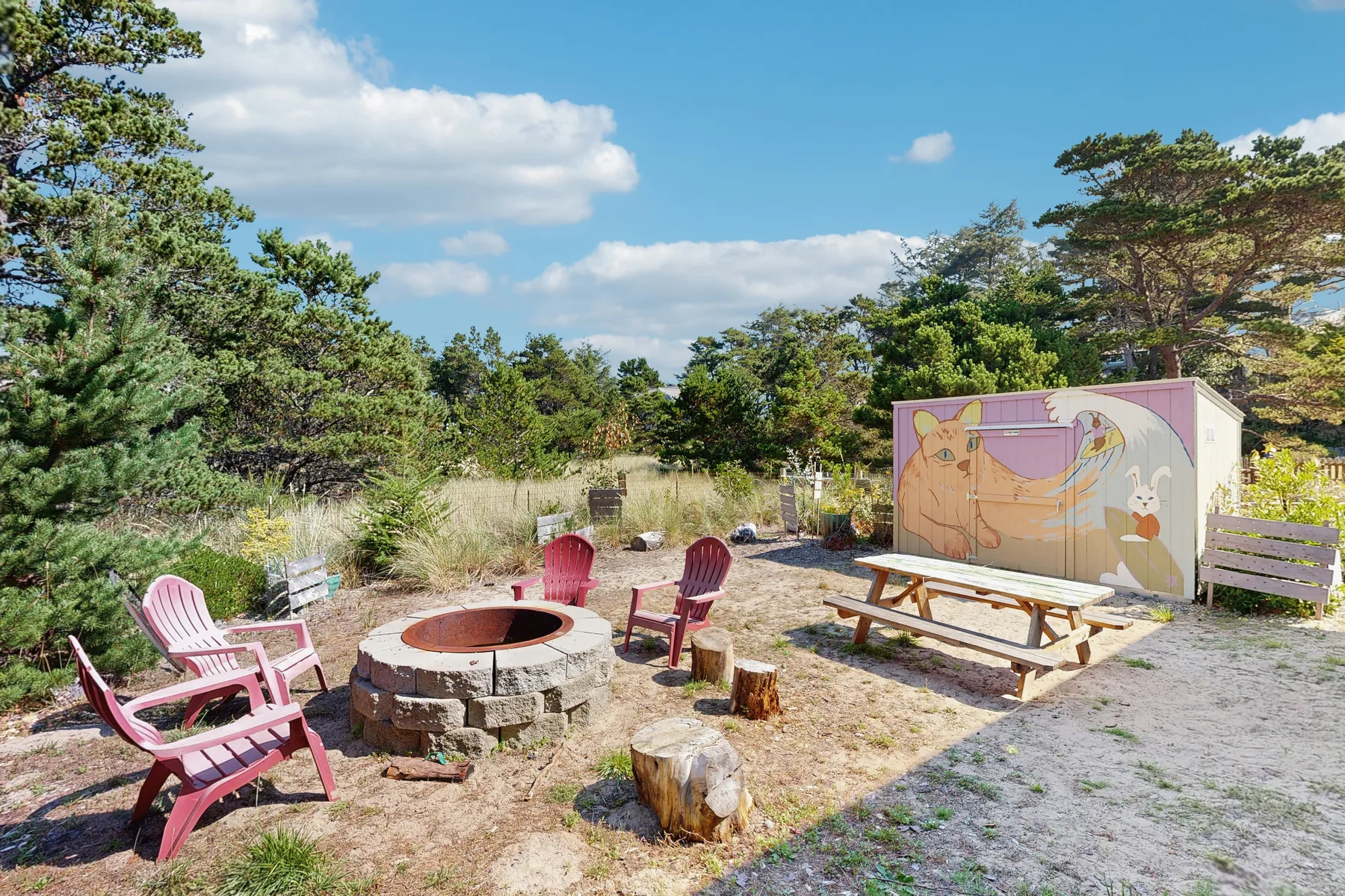 An outdoor seating area features a circular fire pit and a picnic table.