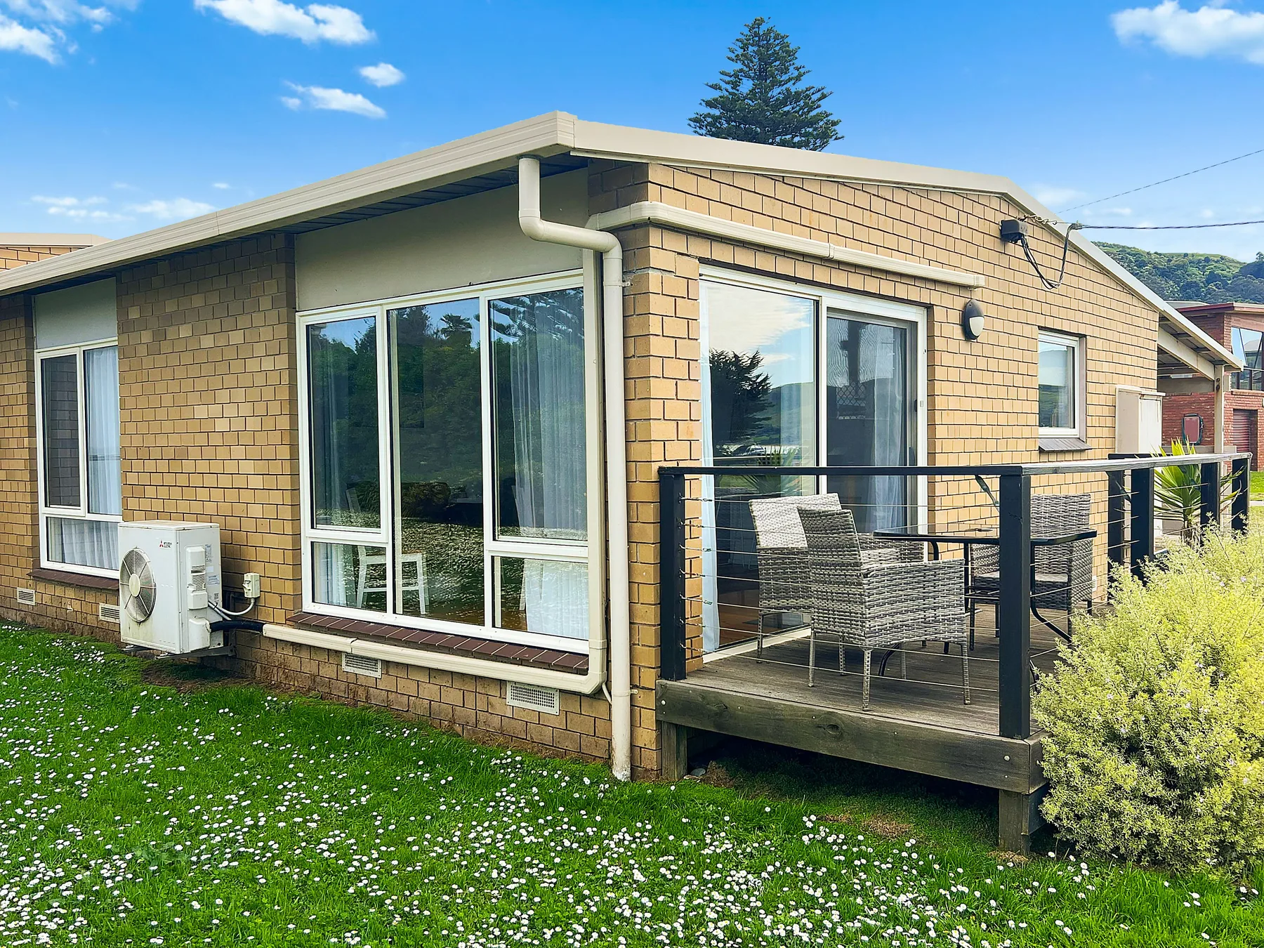 A low brick house with large windows and a small raised deck.