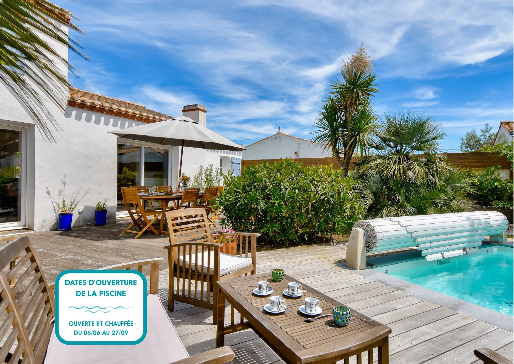 A patio seating area beside a swimming pool, with garden plants and a table.