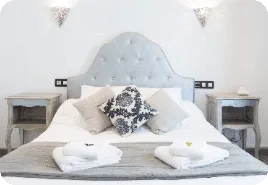 Espacio representativo del hotel: Un dormitorio con una cama bien hecha y cojines decorativos.