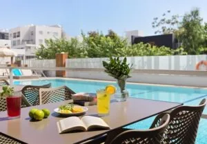 Espacio representativo del hotel: Una zona de estar al aire libre junto a la piscina, con una mesa al lado del agua.