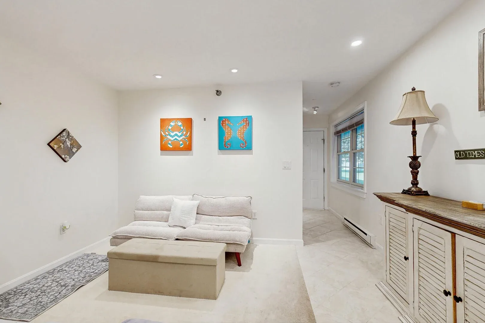 Una sala luminosa con una zona de asientos baja y cuadros coloridos en la pared.