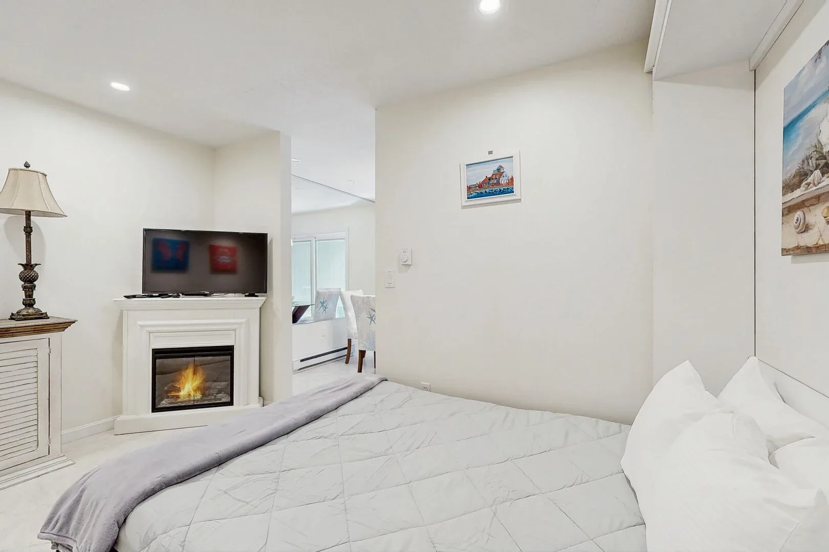 Un dormitorio con una cama bien arreglada y un televisor sobre la chimenea.