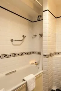 Representative hotel space: A tiled bathroom with a bathtub and wall-mounted towel bars.