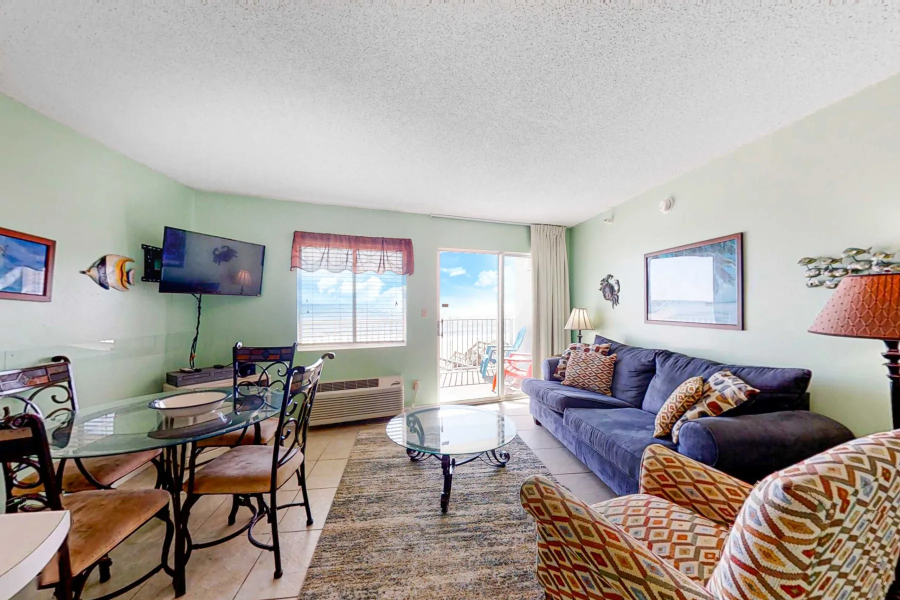 A living room with seating, a glass coffee table, and a dining area by the windows.